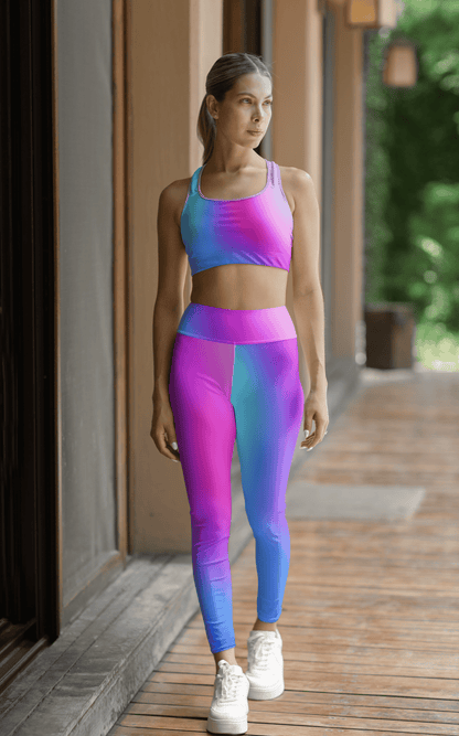 Woman wearing a gradient Cool Colors sports bra and High Waist Yoga Leggings set on a wooden deck. - Printspirationz